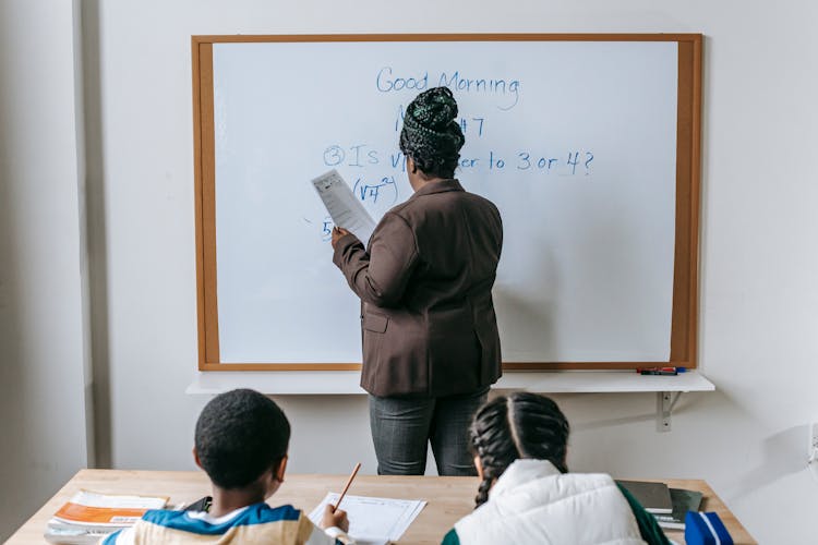Math teacher explaining word problems to students at a whiteboard
